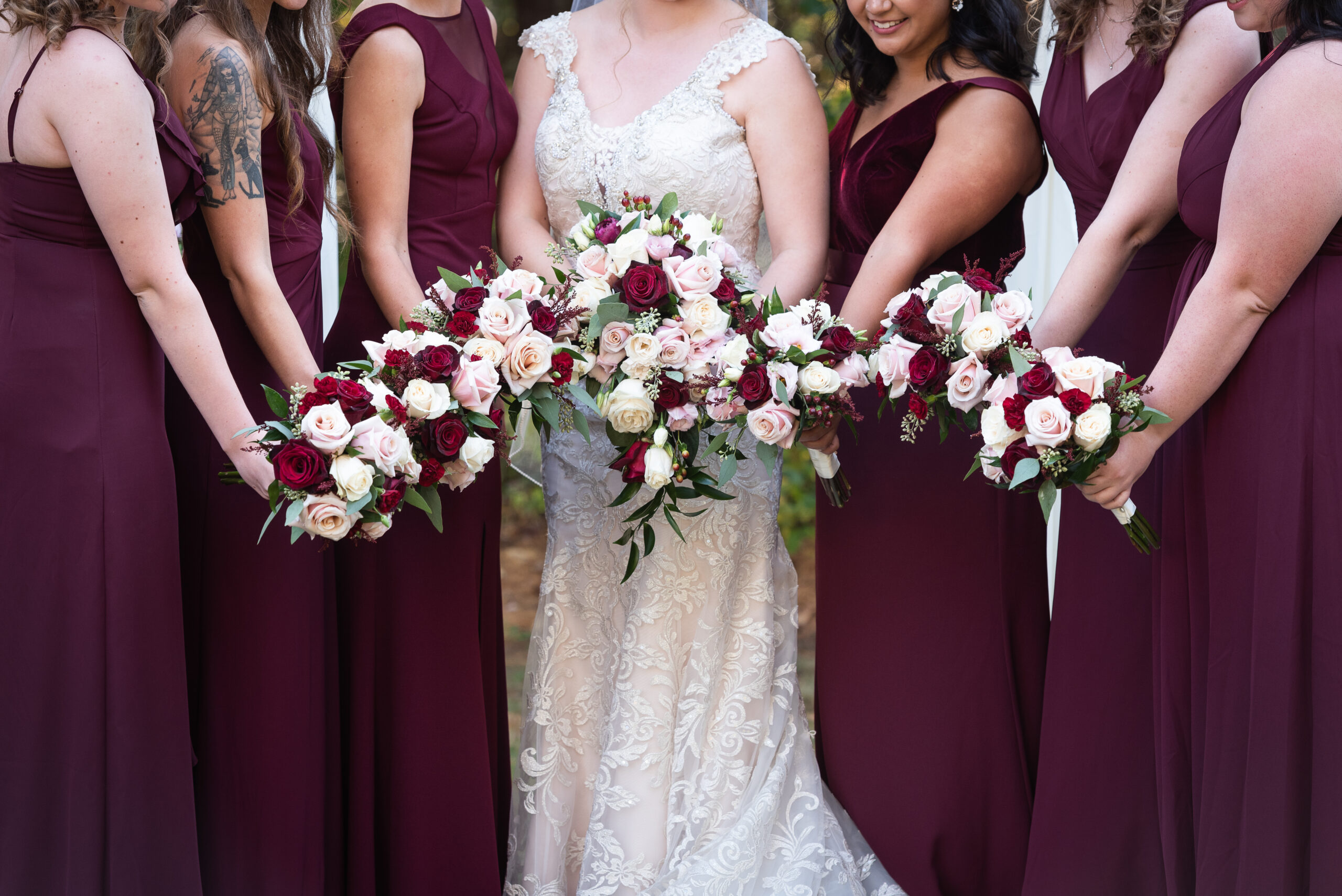 bride and bridesmaids in maroon holding out their flowers Lord Thompson Manor Wedding