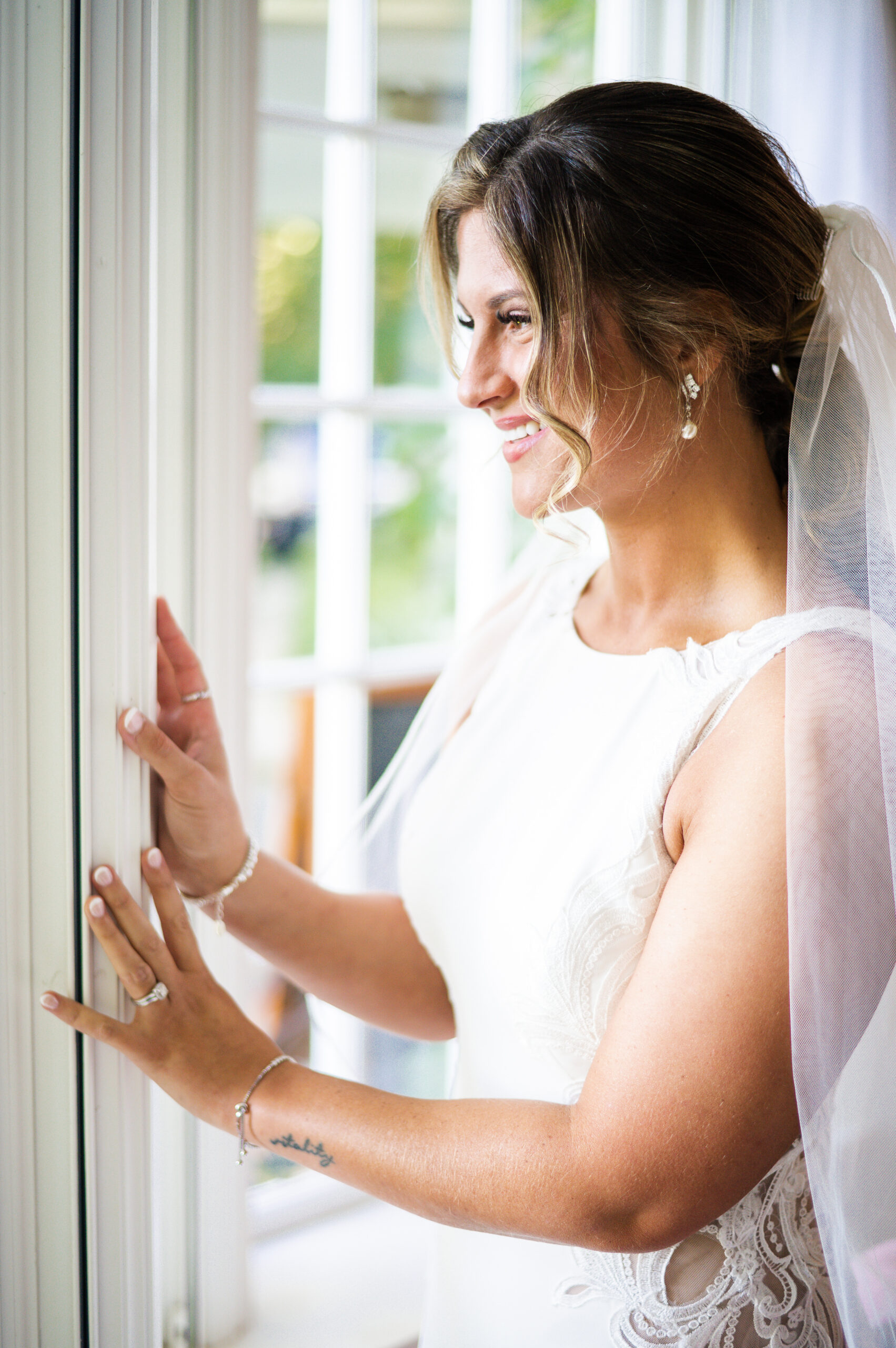 bride in a white gown and veil looking out the window at her saphire estate wedding