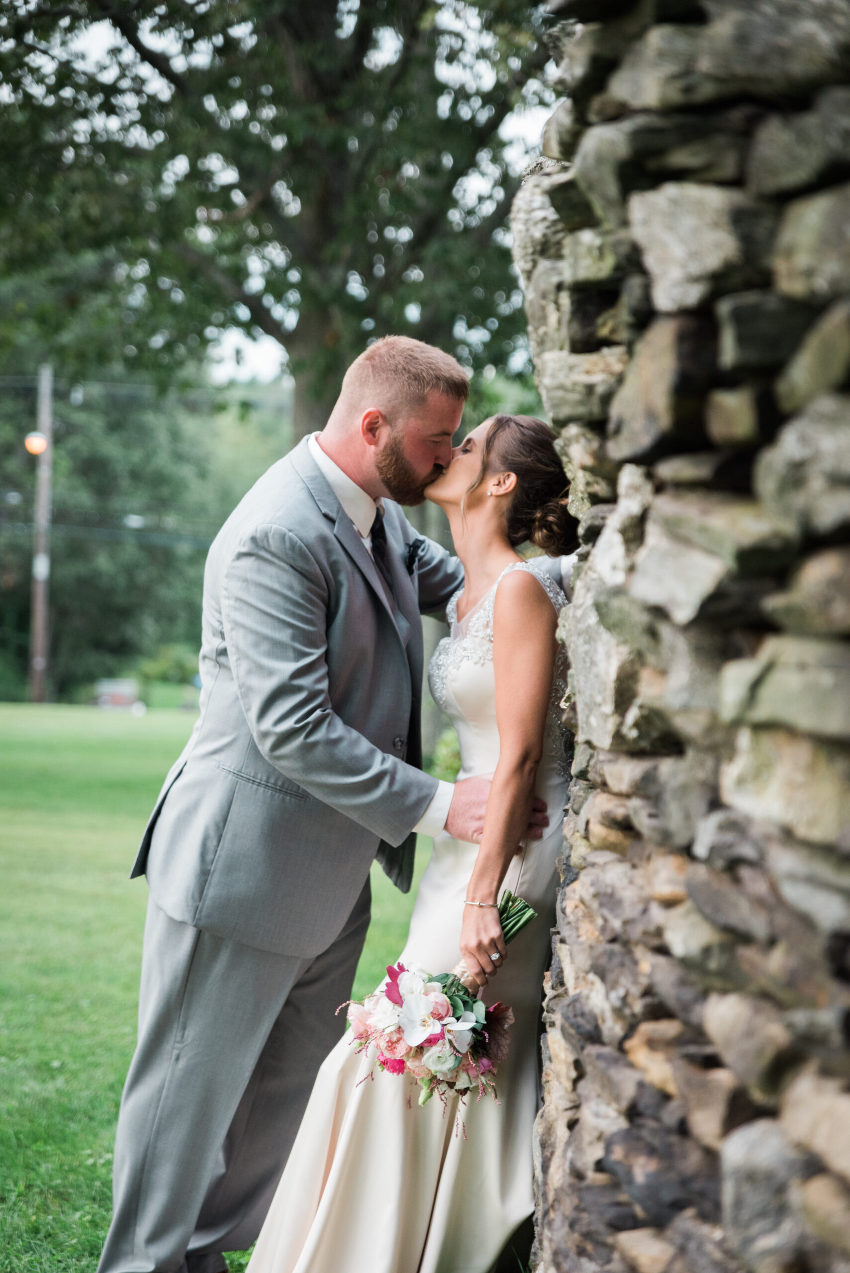 groom and bride leaning against a stone wall at the conner center wedding