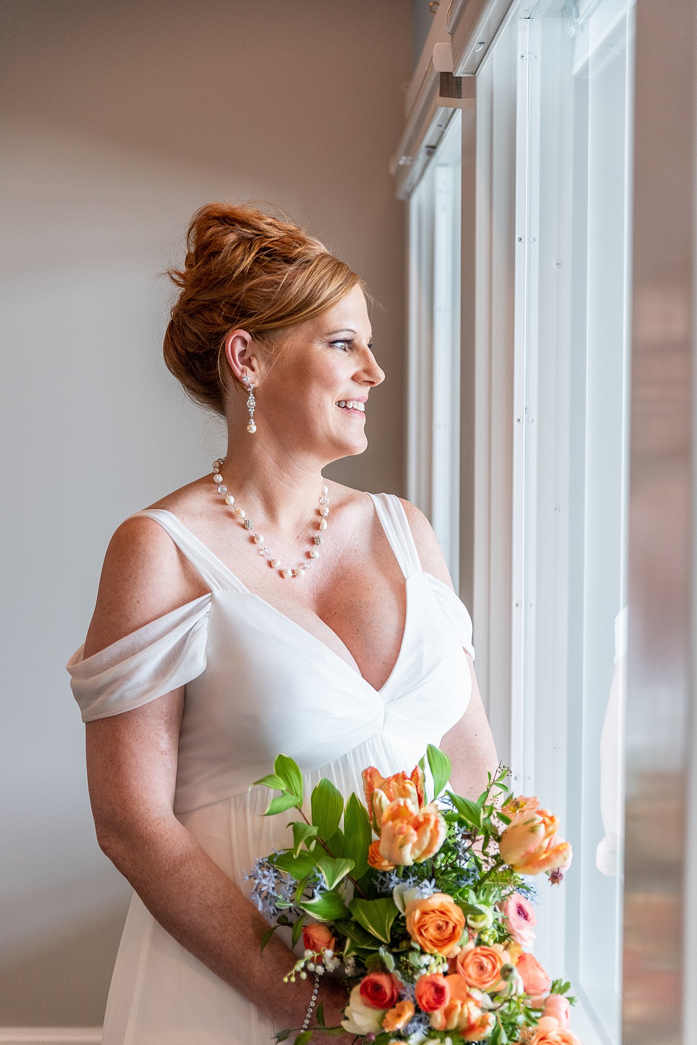 bride looking out the window holding her flowers at her Avenir Wedding