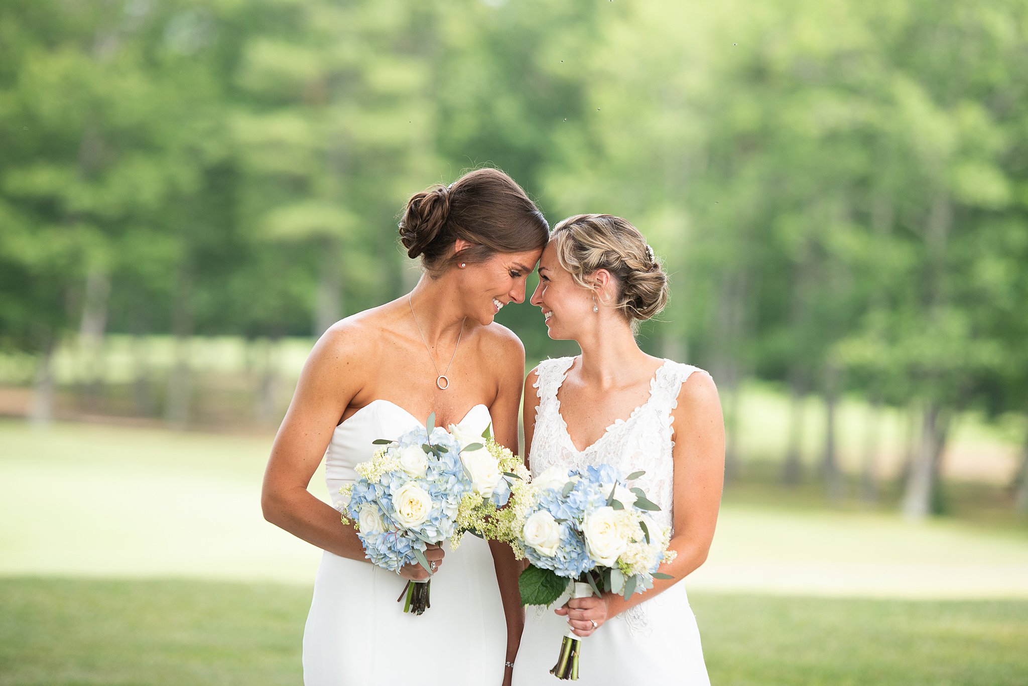 brides in their gowns holding their bouquets with their foreheads together endicott estate wedding